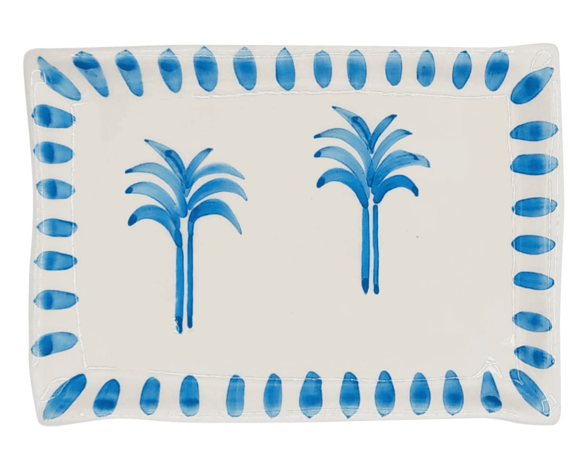 A rectangular ceramic plate with two palm trees painted in the centre in a bring blue. The rim is bright blue large dots.