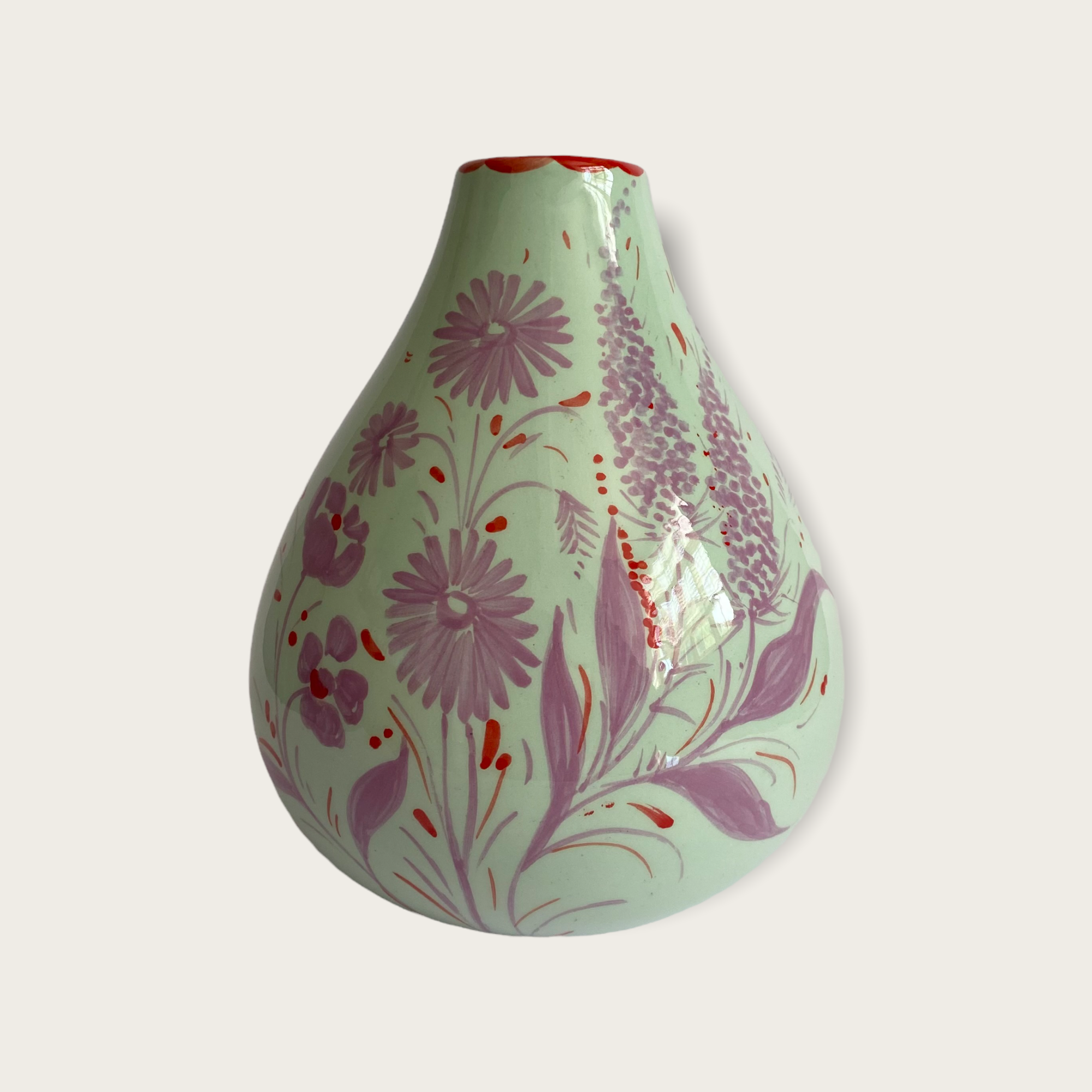 A mint green coloured vase in a bulb shape with handpainted florals in lilac with touches of red.