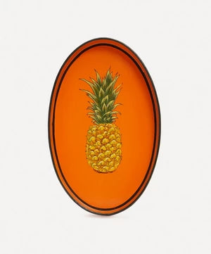 An oval shaped iron tray that features a hand-painted illustration of a pineapple on an orange background.