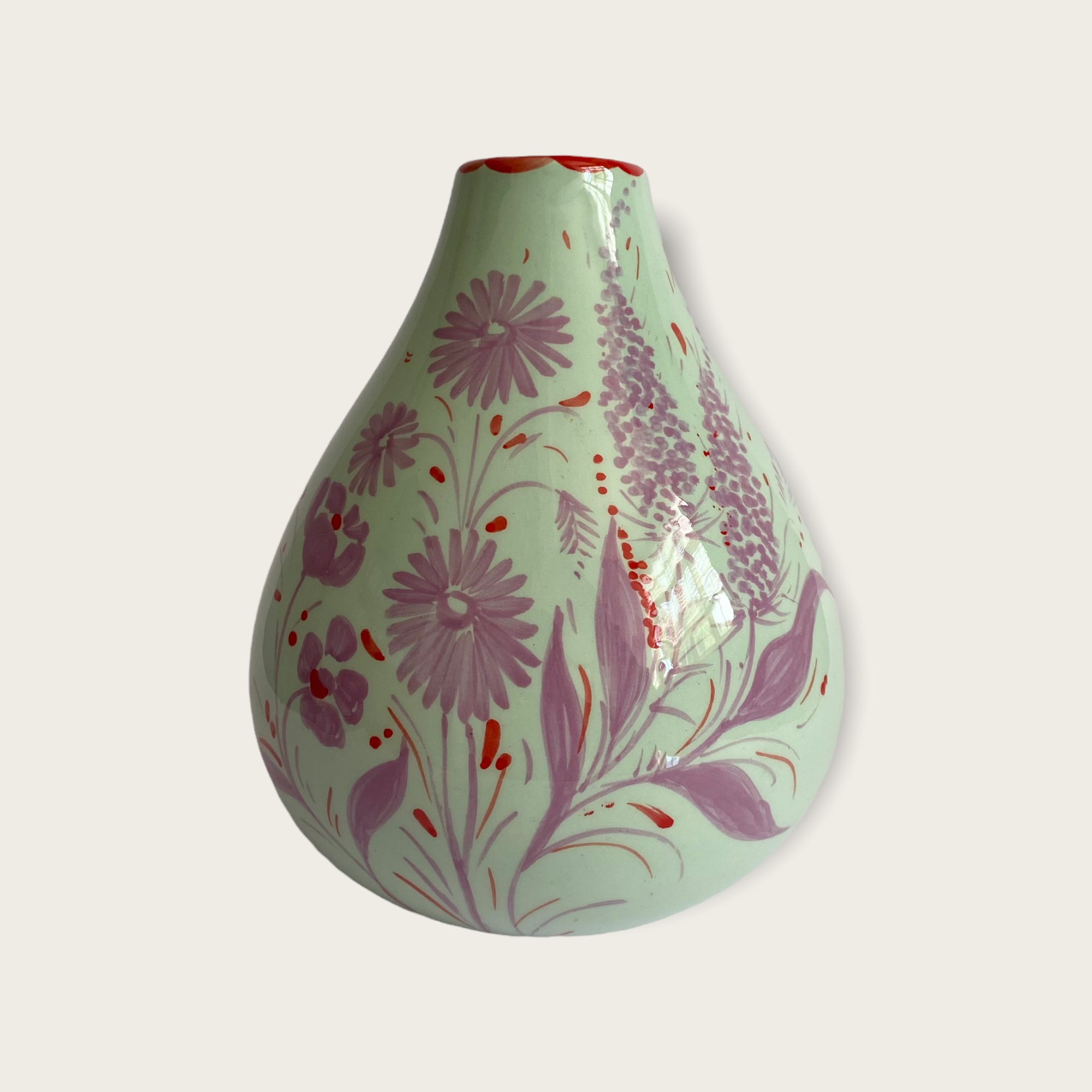 A mint green coloured vase in a bulb shape with handpainted florals in lilac with touches of red. 